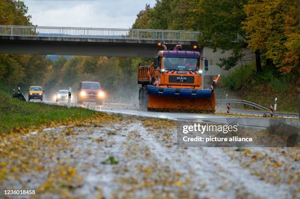 October 2021, Rhineland-Palatinate, Börfink: A vehicle of the Landesbetrieb Mobilität clears leaves and branches from the carriageway on the B52 near...
