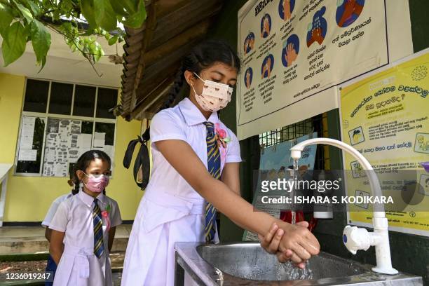 Students wearing facemasks wash their hands inside their Buddhist school in Maharagama, a suburb of the capital Colombo return to classes on October...