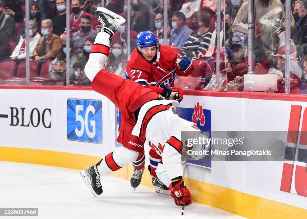 Alexander Romanov of the Montreal Canadiens takes down Andrei Svechnikov of the Carolina Hurricanes along the boards during the first period at...