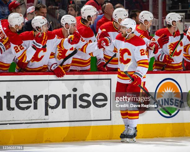 Elias Lindholm of the Calgary Flames pounds gloves with teammates on the bench after scoring a goal during the first period of an NHL game against...