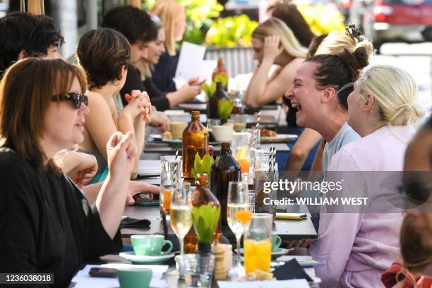 People enjoy a meal at a cafe in Melbourne on October 22 following the midnight lifting of coronavirus restrictions in one of the world's most...