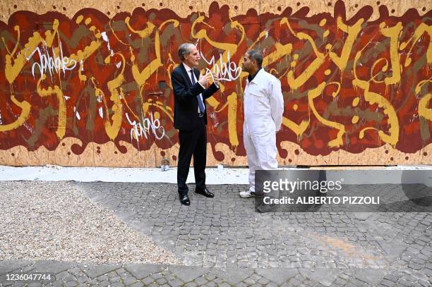 Street artist Artist JonOne, known for a abstract expressionist-styled graffiti, talks with French Ambassador to Italy Christian Masset by his piece...
