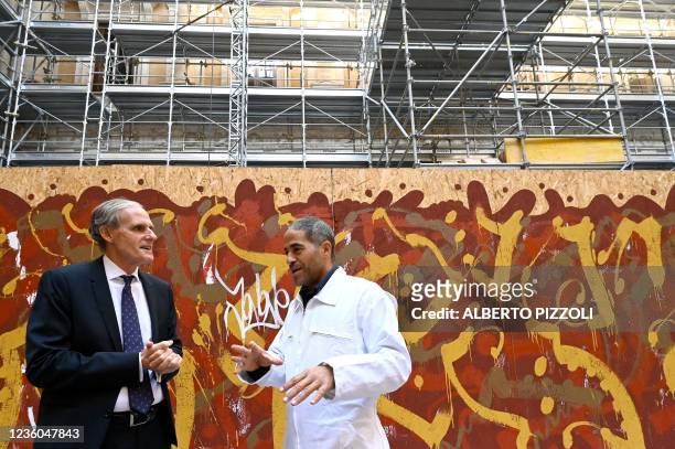 Street artist Artist JonOne, known for a abstract expressionist-styled graffiti, talks with French Ambassador to Italy Christian Masset by his piece...