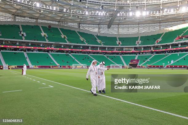 Qatari officials walk on the pitch ahead of the Al-Thumama Stadium in the capital Doha on October 22 ahead of the Amir Cup final football match...