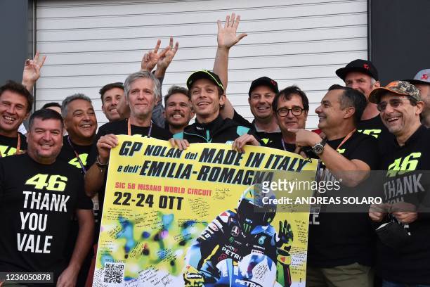 Italian motorcycle road racer and multiple time MotoGP World Champion Valentino Rossi poses with members of the media after they handed him a poster...