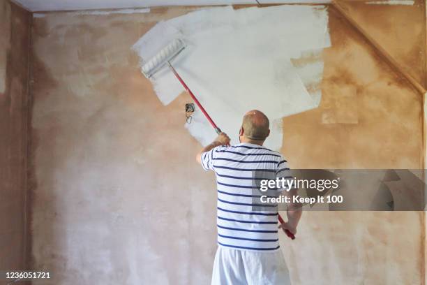 man using a paint roller - decorator stock pictures, royalty-free photos & images