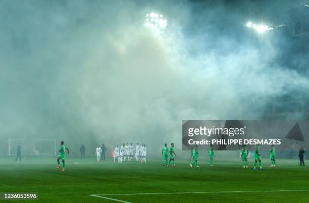 Saint-Etienne and SCO Angers football players wait on the pitch after AS Saint-Etienne supporters launched smoke canisters to protest against the...