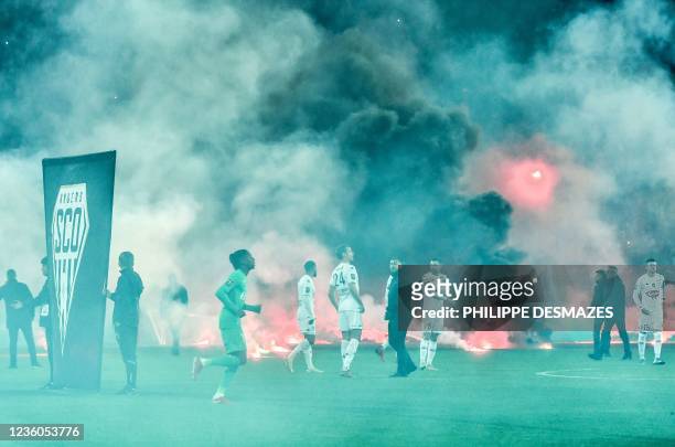 Saint-Etienne and SCO Angers football players react on the pitch after AS Saint-Etienne supporters launched smoke canisters to protest against the...