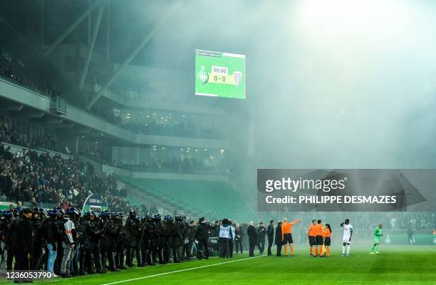 Referees speak with delegates of the French Football Federation as French riot police members stand guard, after AS Saint-Etienne supporters launched...