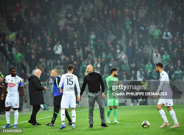 Anger's French head coach Gerald Baticle and his players leave the field under the protection of French riot police, after AS Saint-Etienne...