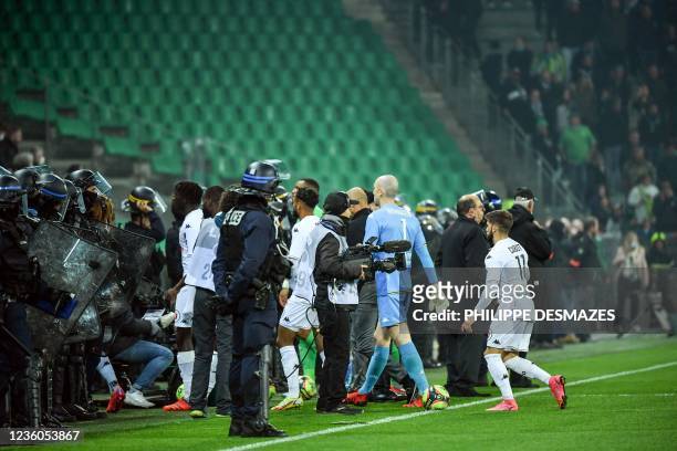 Angers football players leave the field under the protection of French riot police, after AS Saint-Etienne supporters launched smoke canisters to...