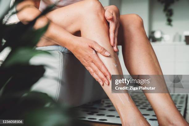unkenntlich erkennbare frau massiert körperlotion auf ihren beinen - body lotion stock-fotos und bilder