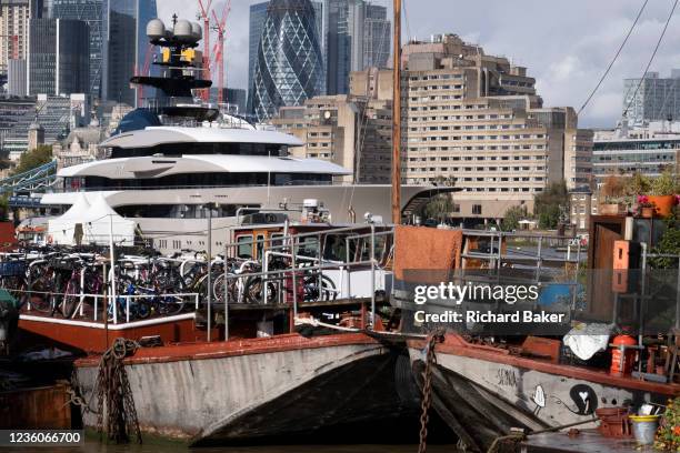 With heritage barges and 'lighters' in the foreground, the superyacht Kismet dominates the river Thames, on 20th October 2021, in London, England....