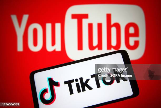 In this photo illustration a TikTok logo is seen on a smartphone screen with a YouTube logo of an online video sharing and social media platform in...