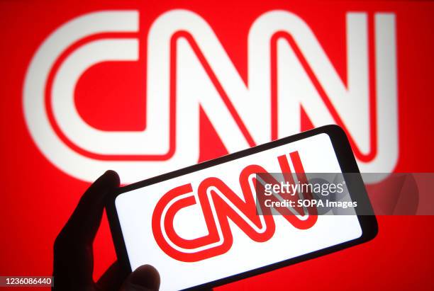 In this photo illustration a CNN logo is seen on a smartphone and a pc screen.