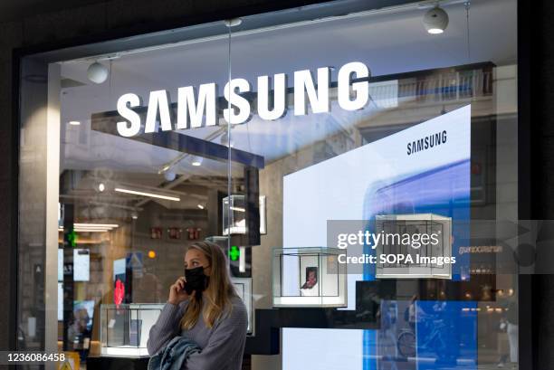 Woman talks on the mobile phone in front of a Samsung mobile shop in Valencia.