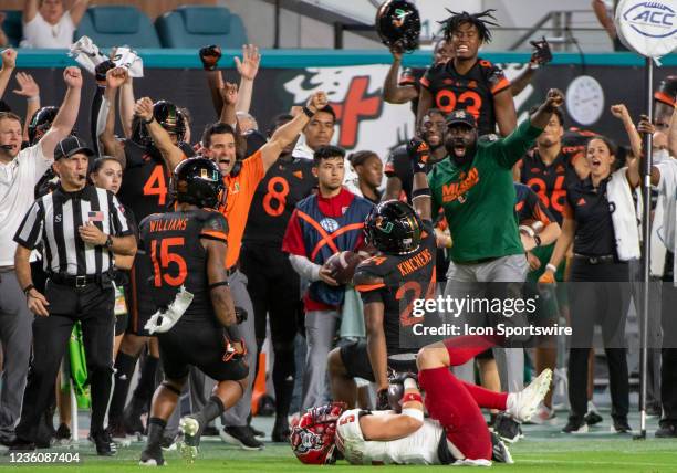 Miami head coach Manny Diaz yells along with his team on the sidelines as they celebrate Miami safety Kamren Kinchens stopping NC State wide receiver...