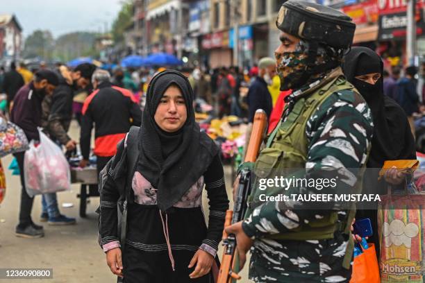 An Indian paramilitary trooper stands guard at a market in Srinagar on October 24, 2021.