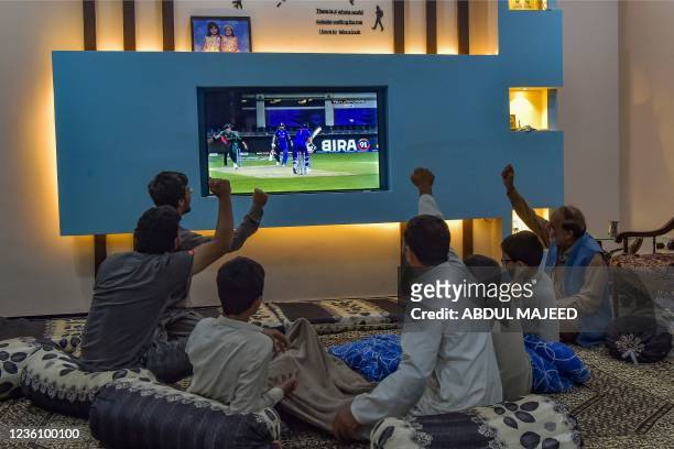 Family watches the live telecast of the T20 cricket World Cup match between India and Pakistan happening in Dubai on a television in their home in...