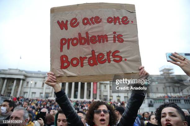 People hold banners as 'Little Amal,' a 3.5-meter-tall puppet representing a young Syrian refugee girl, arrives for a 10th birthday party in...