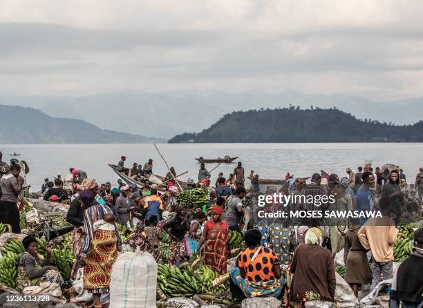 Traders unload their goods into a motorised pirogue on the shores of Lake Kivu in Goma on October 21, 2021. - In the north and south of Lake Kivu, in...