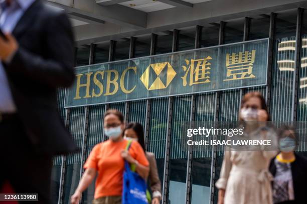 People walk past the HSBC bank headquarters in Hong Kong on October 25, 2021.