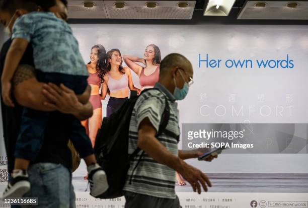 Commuters walk past the Women's underwear clothing brand Her Own Words at a MTR subway station in Hong Kong.