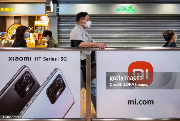 Commuters walk past the Chinese technology electronics brand Xiaomi Mi 11T 5G smartphone advertisement at a MTR subway station in Hong Kong.