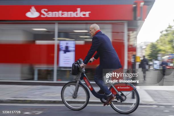 An office worker using a Santander Cycle hire bike travels passes a Banco Santander SA bank branch in London, U.K., on Friday, Oct. 22, 2021. The...