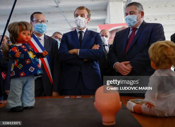 French President Emmanuel Macron , next to Mayor of Montbrison, Christophe Bazile , looks at a doll as he visits the "Gege" industrial wasteland,...