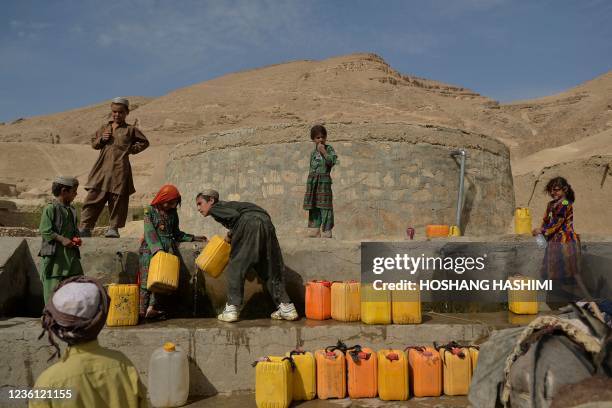 This picture taken on October 15, 2021 shows children filling jerrycans with water from a water storage in Bala Murghab district of Badghis province....