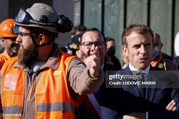 French President Emmanuel Macron stands next to a worker as he visits the "Gege" industrial wasteland, site of former French toy manufacturer "GeGe",...