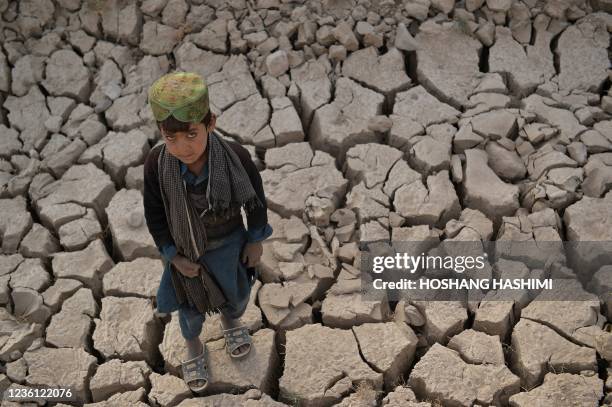 This picture taken on October 15, 2021 shows a child standing on a dry land in Bala Murghab district of Badghis province. - Drought stalks the...