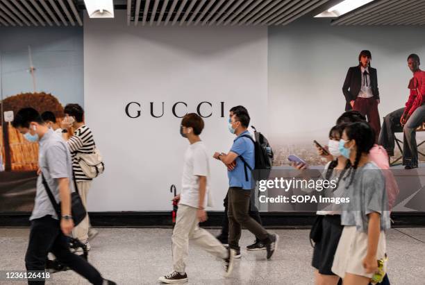 Commuters walk past a commercial advertisement of the Italian luxury fashion brand Gucci at MTR subway station in Hong Kong.