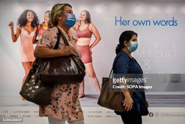 Women walk past the Women's underwear clothing brand Her Own Words at a MTR subway station in Hong Kong.