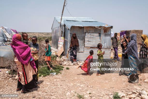 People stand outside of their homes in an informal settlement of internally displaced people in the outskirts of the city of Hargeisa, Somaliland, on...