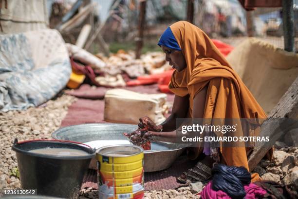 Yurub Abdi Jama, 35 years old and mother of 8 children, washes clothes at her home in an informal settlement of internally displaced people in the...