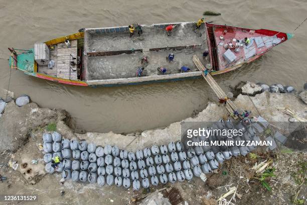 In this aerial picture taken on September 20 workers place geo-textile bags to prevent river erosion on the banks of river Padma in Manikgonj. -...