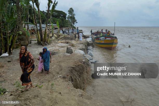 In this picture taken on September 20 locals walks past an eroded section on the banks of river Padma in Manikgonj. - Bangladesh, a low-lying nation...