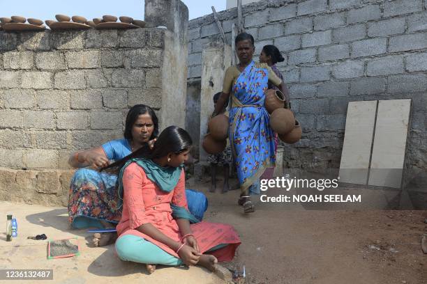 Woman carries earthen pots to dry outside her home ahead of the forthcoming Diwali festival on the outskirts of Hyderabad on October 26, 2021.