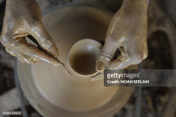 Potter makes 'diyas' or earthenware oil pots, at his home ahead of the forthcoming Diwali festival on the outskirts of Hyderabad on October 26, 2021.