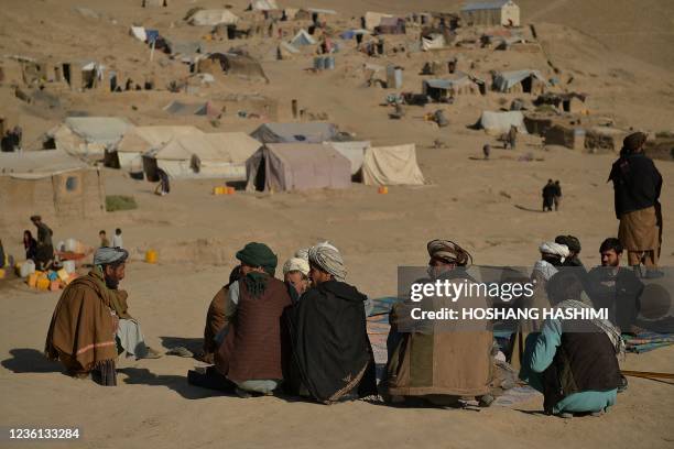 This picture taken on October 17, 2021 shows men sitting at an Internally Displaced People camp in Qala-i-Naw, Badghis Province. Child marriage has...