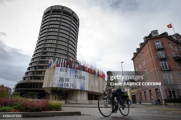 Man rides his bicycle past the building of the Bank for International Settlements that celebrates its 90th anniversary in Basel on October 22, 2021....