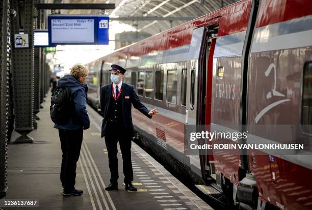 Ticket inspector speaks to a passenger as they stand near a carriage of the revamped Thalys train at Amsterdam Central railway station, on October...