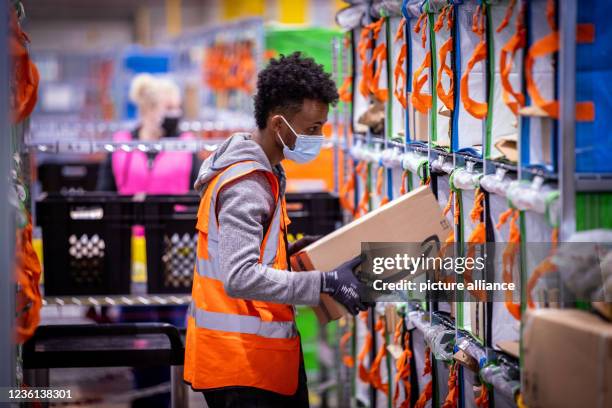 October 2021, Mecklenburg-Western Pomerania, Neubrandenburg: Employees sort parcels from online retailer Amazon at the new distribution center. The...