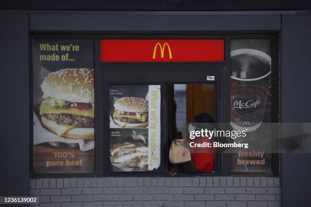 An employee waits for a customer to pickup food in the drive-thru window of a McDonald's Corp. Fast food restaurant in Louisville, Kentucky, U.S., on...