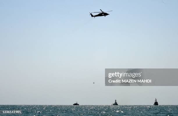 Navy Martin UAV drone hovers mid-air beneath a US Navy SH-60S Seahawk helicopter, while Bahraini Coast Guard ship Deraa 13 , US Coast Guard cutter...