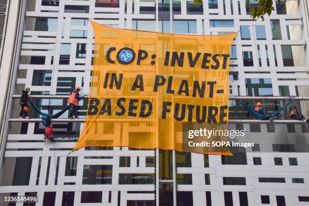 Activists are seen next to a banner, calling on the government to invest in a plant-based future at COP26 , on the Home Office building during the...