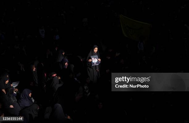 An Iranian veiled woman holds a poster with portraits of Iran's Supreme Leader Ayatollah Khamenei and Late Leader Ayatollah Ruhollah Khomeini during...