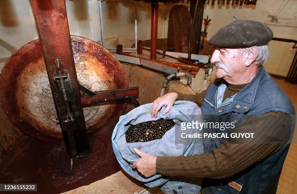 Un oléiculteur s'apprête à déverser un sac d'olive, le 04 décembre 2003, dans un moulin du XVIIe siècle de Drap, un village sur les hauteurs de Nice,...